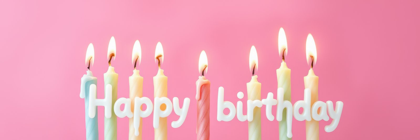 Colorful birthday candles with flames on a pink background celebrating a joyful occasion
